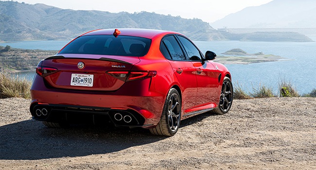 Rear 3/4 shot of a red Giulia QV with an ocean view