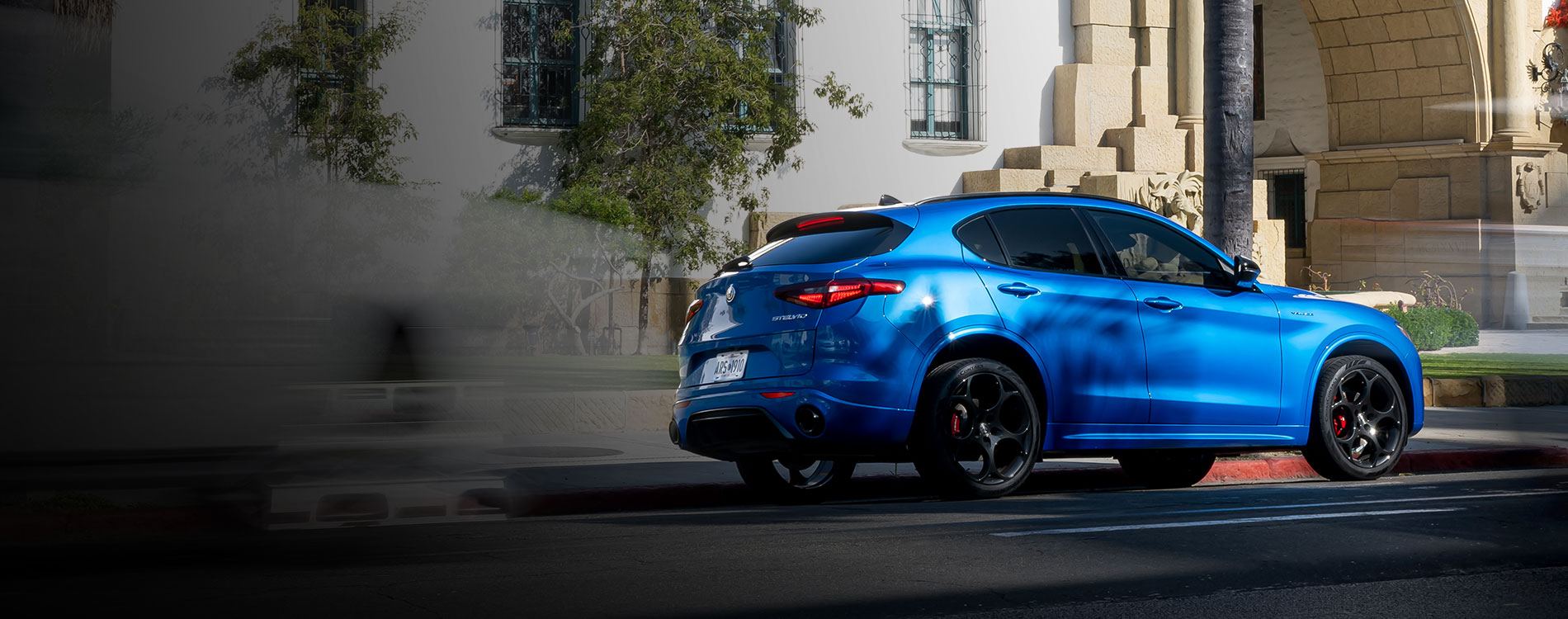 Rear 3/4 shot of a blue Stelvio parked on a road side